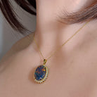Yellow gold-plated opal triplet halo pendant worn at the neckline, close view