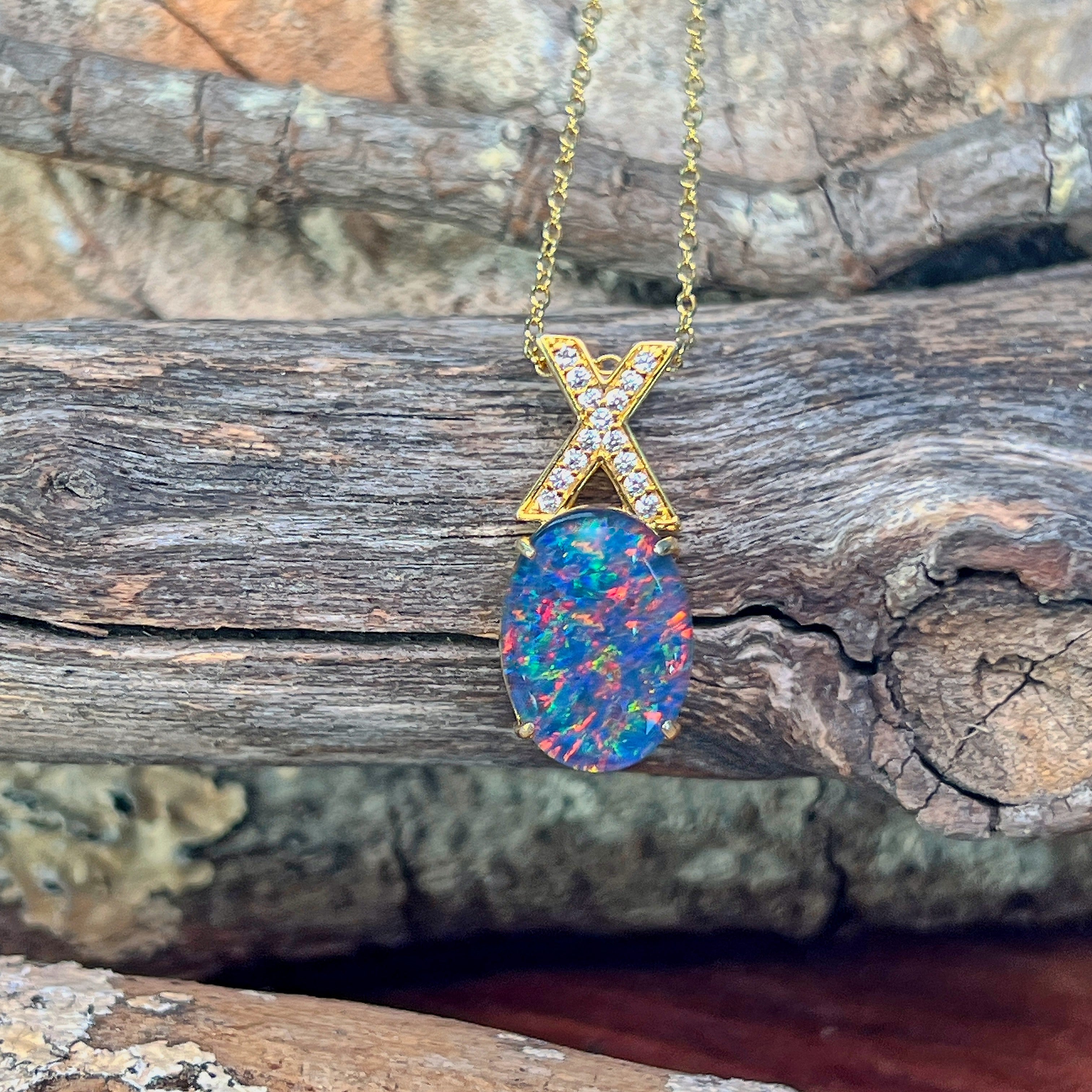 Yellow gold-plated silver opal triplet pendant hanging against weathered driftwood