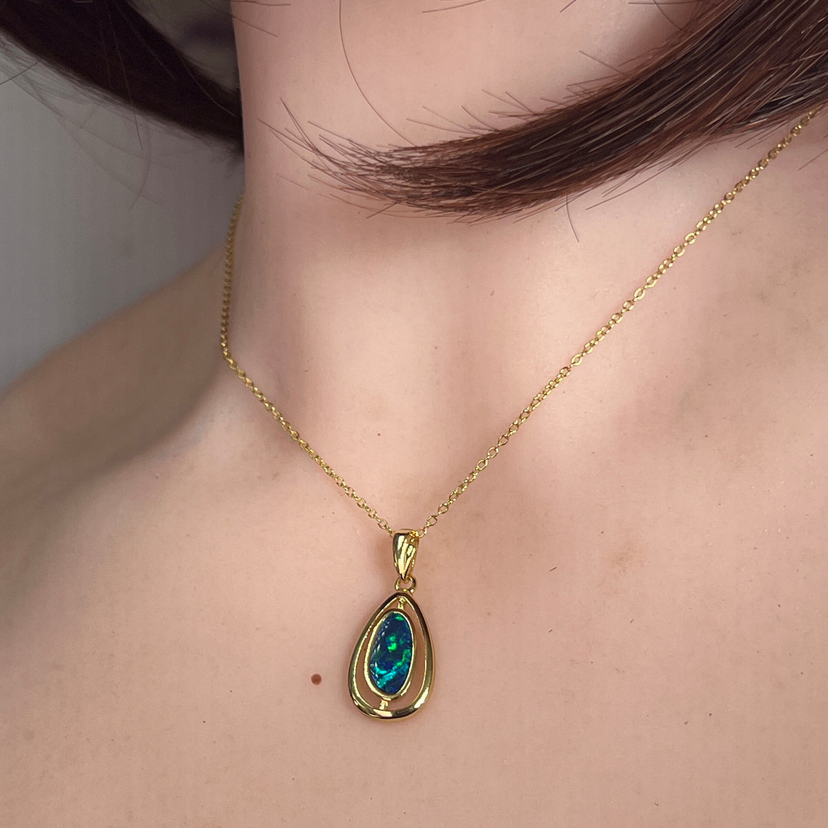 11.5 x 5.5mm freeform Australian opal doublet pendant worn at the neck, yellow gold-plated silver