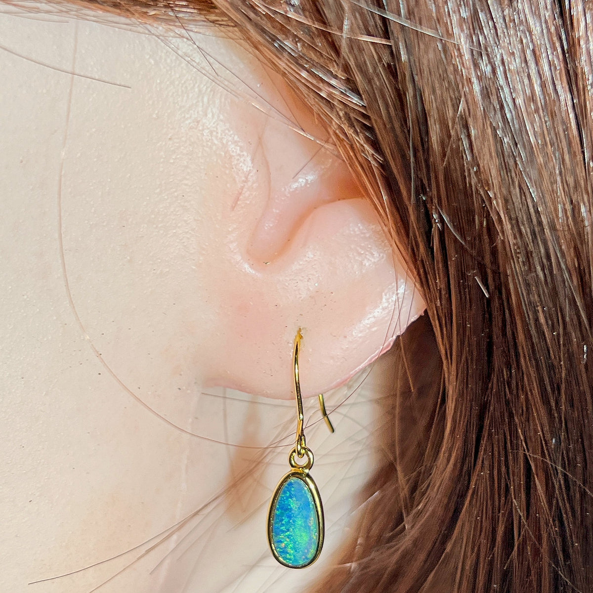 11 x 6mm oval Australian opal doublet earrings worn on the ear, yellow gold-plated silver