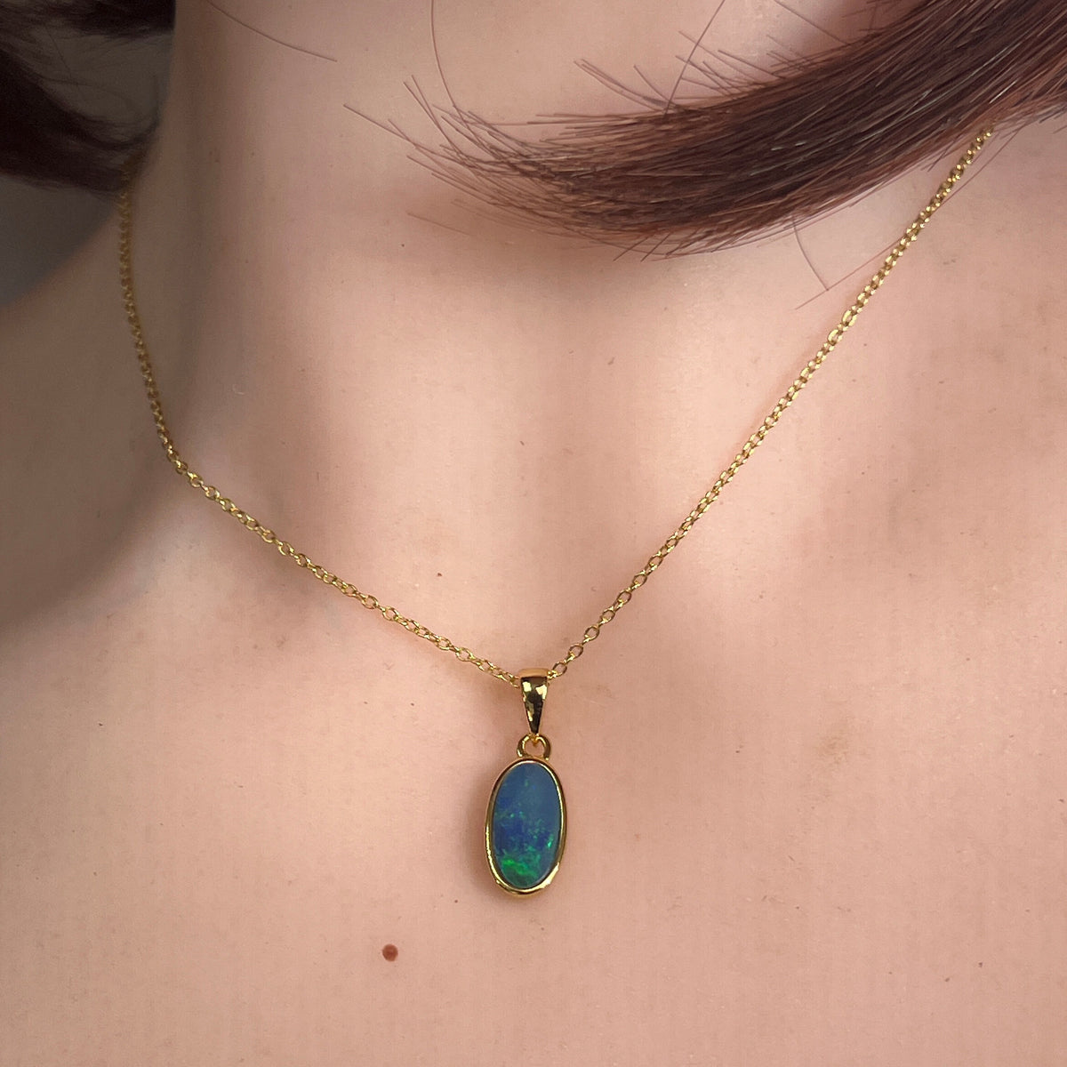 oval Australian opal doublet pendant in yellow gold-plated silver, worn at the neck