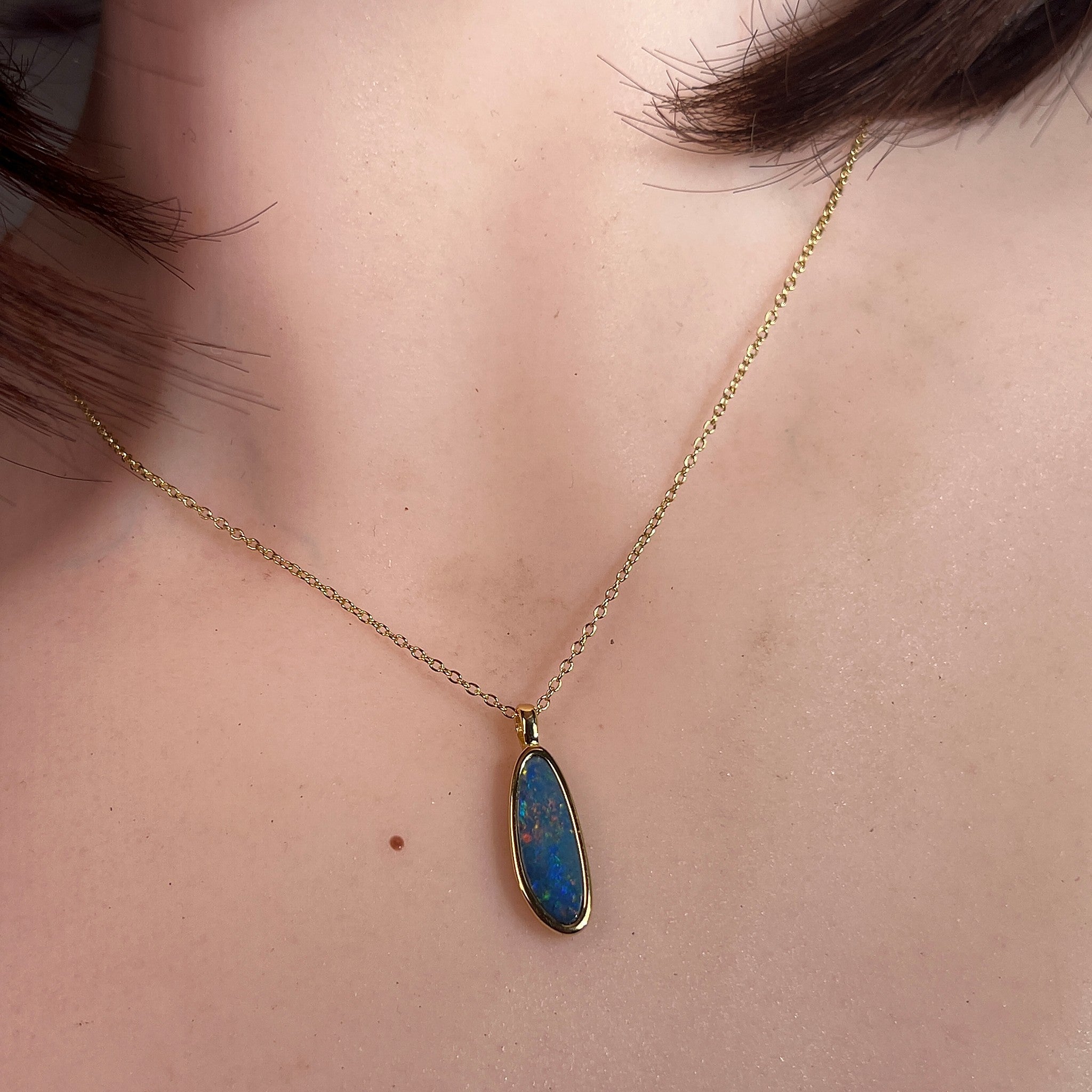 pear-shaped Australian opal doublet pendant in yellow gold-plated silver, worn at the neck