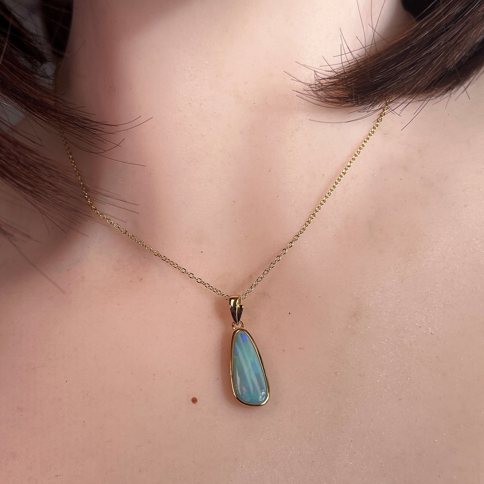 Australian opal doublet pendant worn at the neck, green, blue, red and yellow play-of-colour
