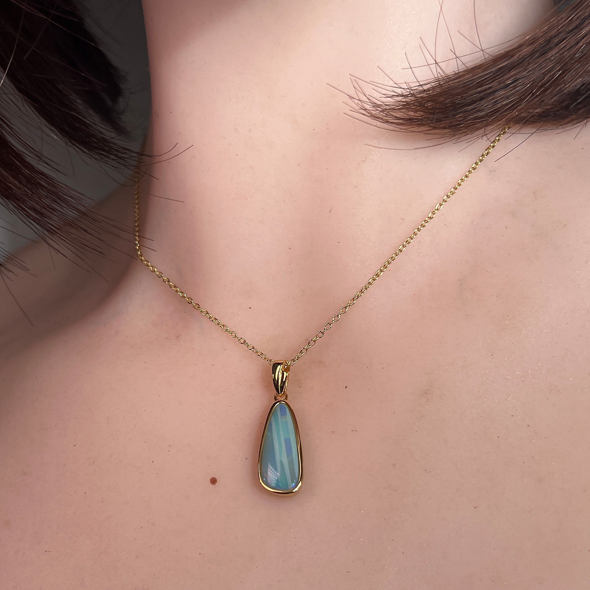 Worn Australian opal doublet pendant in yellow gold-plated silver, green, blue, red and yellow, 17 x 6mm