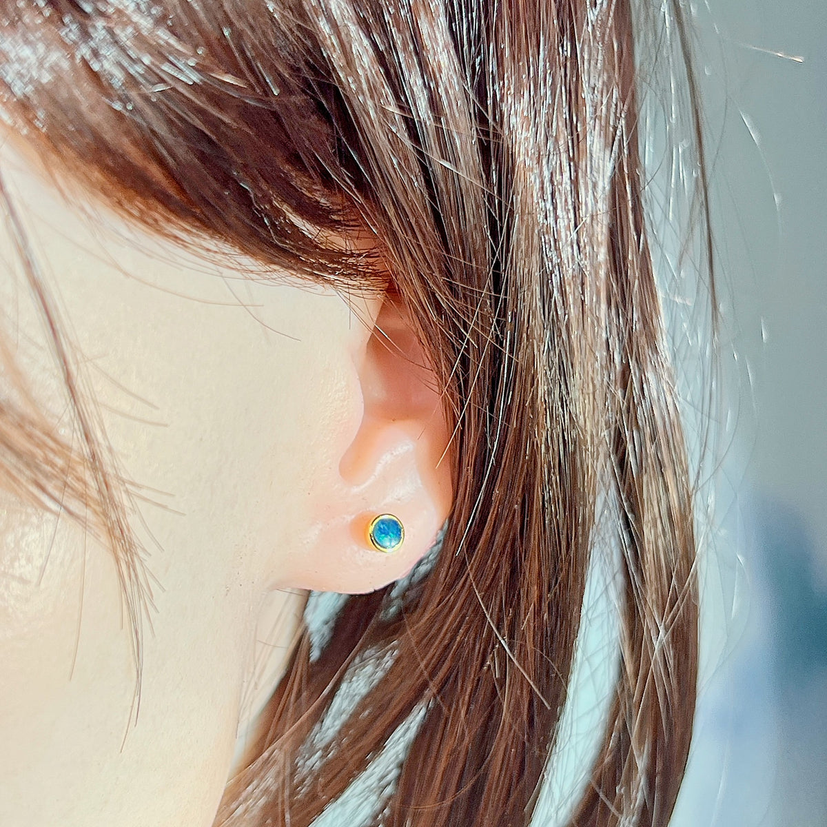 5mm round Australian opal doublet earrings worn on the ear, yellow gold-plated silver
