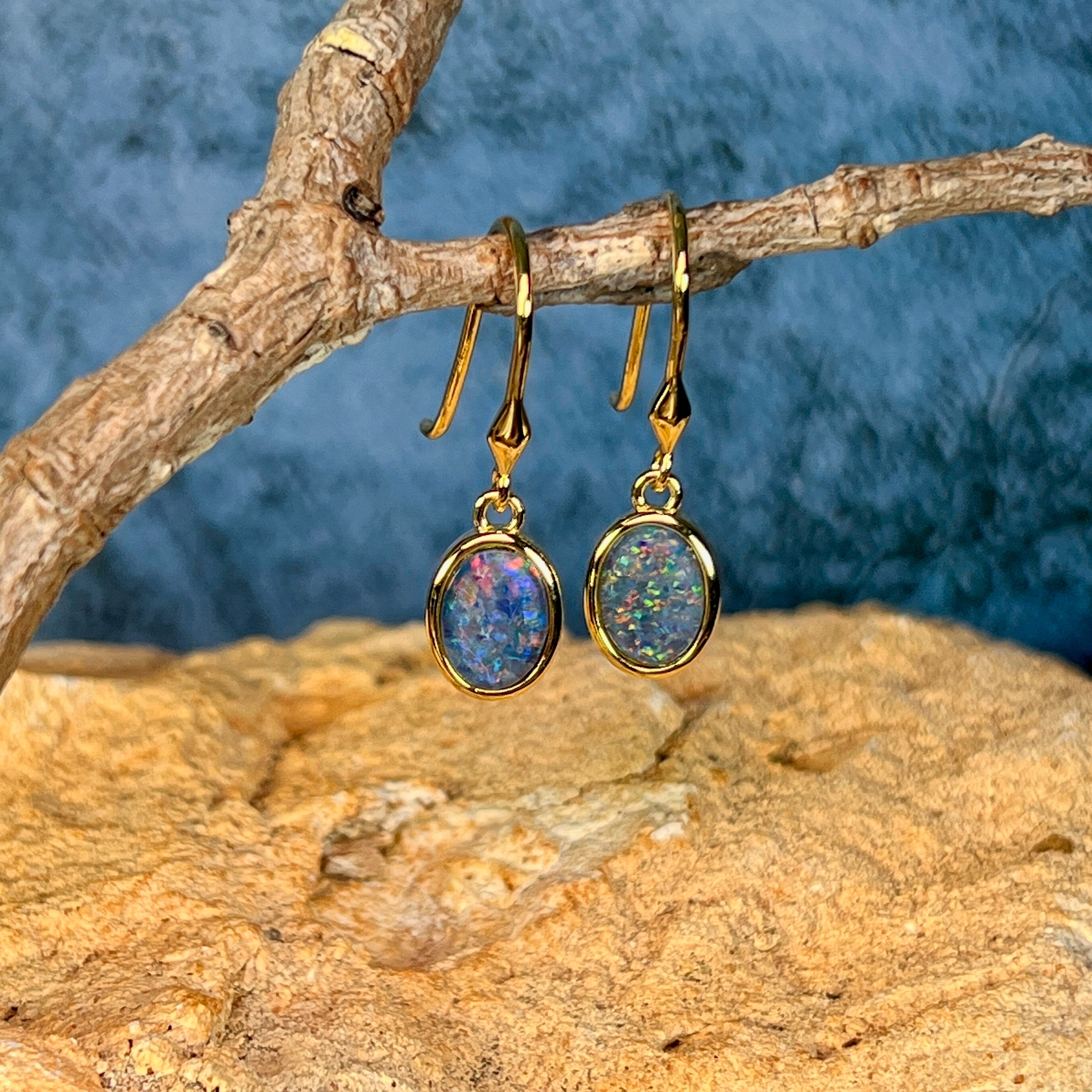 Yellow gold plated sterling silver opal triplet dangling earrings hanging from a driftwood branch
