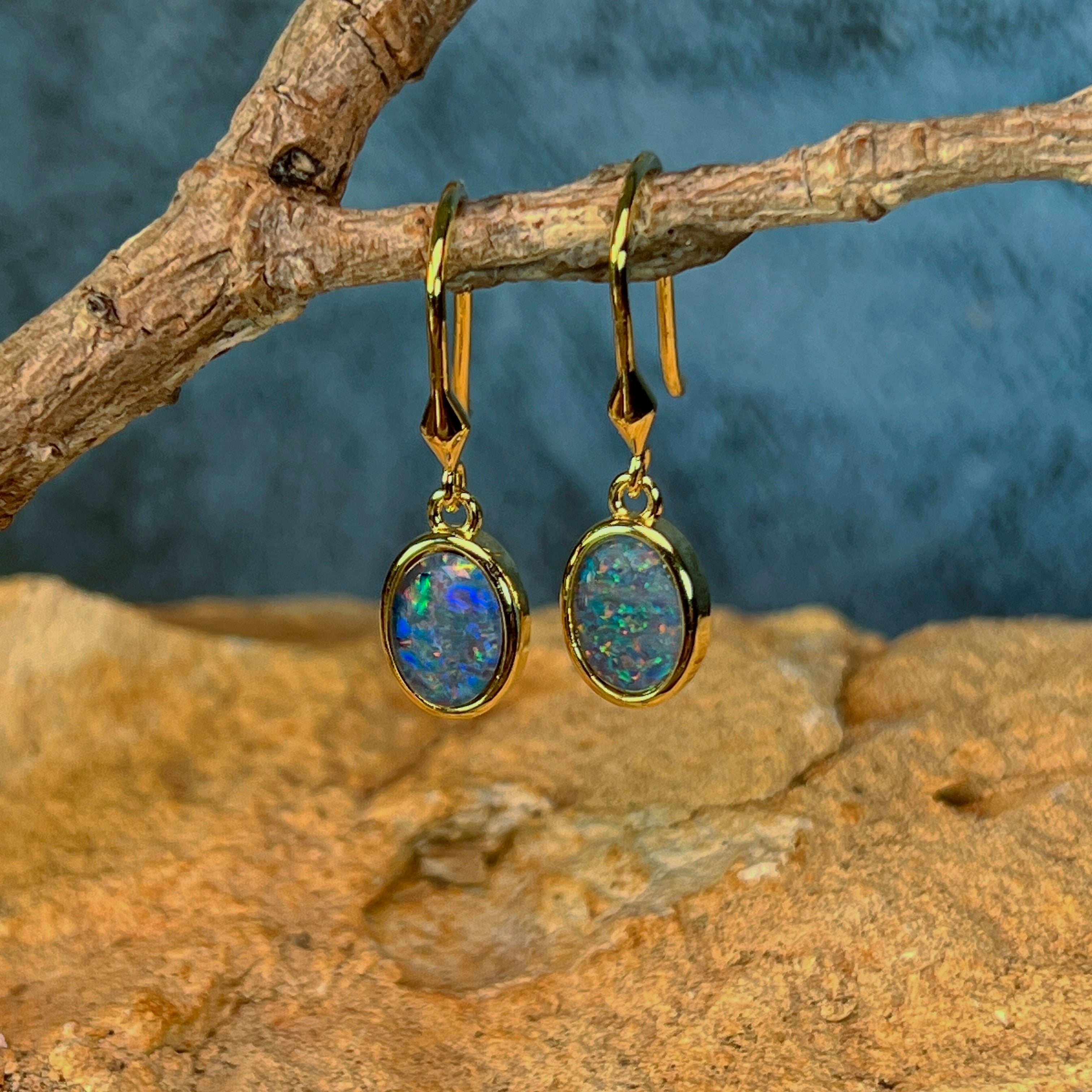 Close view of the oval Australian opal triplets in yellow gold plated bezel settings, hanging on driftwood