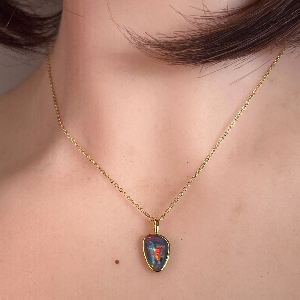Worn Australian opal triplet pendant in yellow gold-plated silver, blue, red and green, 12 x 8mm
