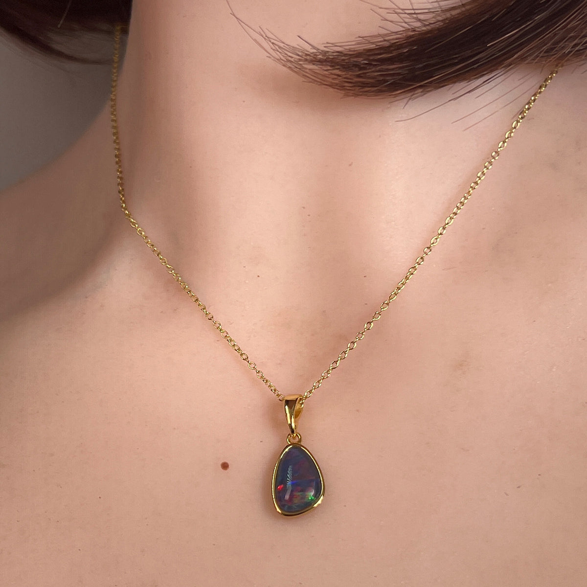 Worn Australian opal triplet pendant in yellow gold-plated silver, red, green and blue, 11 x 8mm