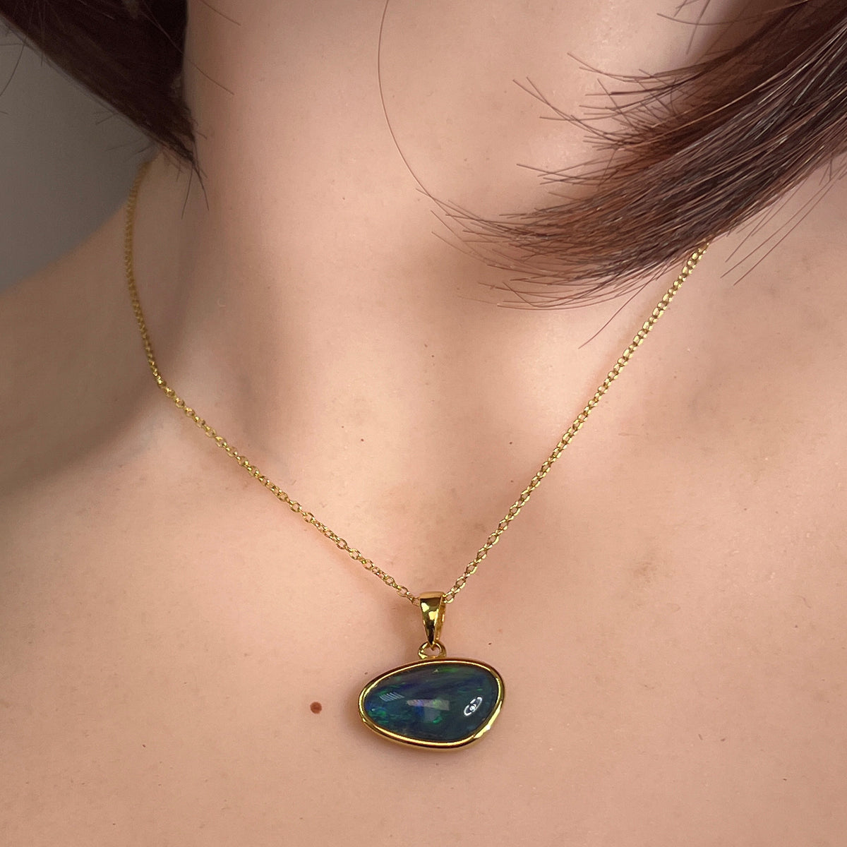 Australian opal triplet pendant worn at the neck, blue and green play-of-colour