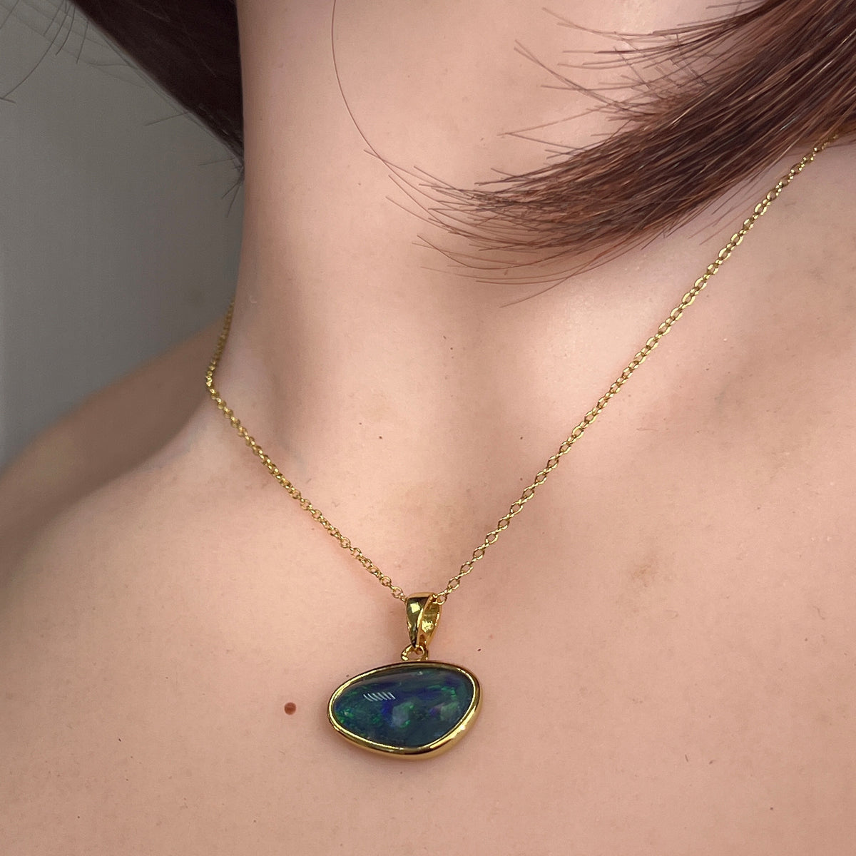16 x 10mm freeform Australian opal triplet pendant worn at the neck, yellow gold-plated silver